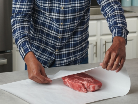 Man wrapping a steak in a piece of freezer paper