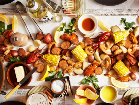 Seafood boil with lobster, corn on the cob, potatoes and lemon wedges lying on a table