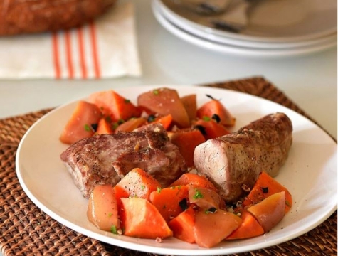 pork tenderloin sitting on a plate surrounded by sweet potatoes