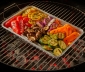 Grill pan sitting on a charcoal grill topped with roasted vegetables