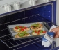 Person removing a baking sheet from the oven lined with parchment paper and personal pizzas 