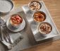 4 air fryer cups filled with cinnamon rolls sitting on a kitchen table
