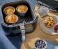 3 air fryer cups filled with muffins sitting in an air fryer basket 