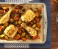 Roasted chicken and vegetables sitting on a parchment lined baking sheet