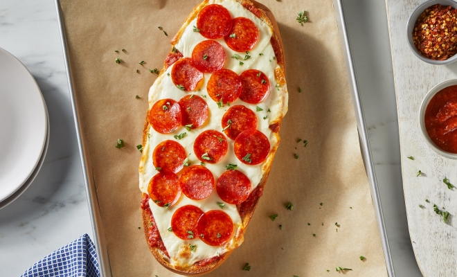 Pepperoni pizza sitting on a parchment lined baking sheet