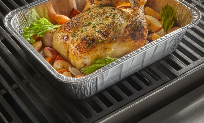 Roasted chicken and vegetables sitting in a pan on the grill