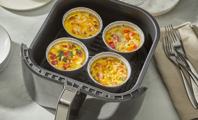 4 air fryer cups filled with egg bites sitting in an air fryer basket