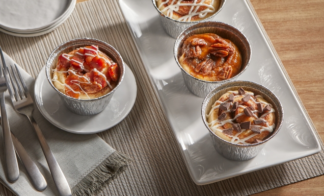 4 air fryer cups filled with cinnamon rolls sitting on a kitchen table