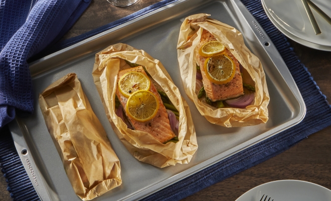 Salmon sitting in a parchment packet on top of a baking sheet
