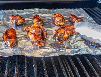 Chicken wings sitting on Reynolds Wrap non-stick aluminum foil on the grill
