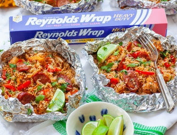 Chicken jambalaya in foil packets sitting alongside a box of Reynolds Wrap Heavy Duty Foil