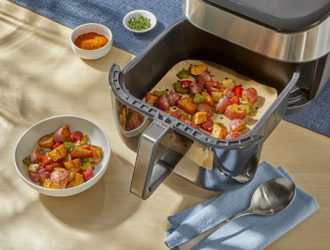 breakfast potatoes in an air fryer basket lined with an air fryer liner