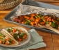 Spiced sweet potato and kale tacos sitting alongside an open aluminum foil grill bag set on top of a wooden table