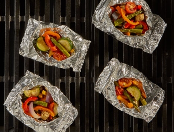 foil packets with mixed vegetables sitting on the grill