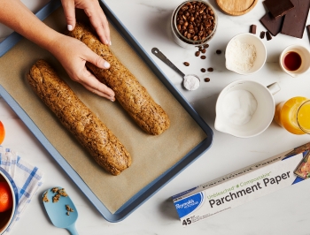 Two logs of dough being shaped on a parchment lined baking sheet, showing the process of making the recipe